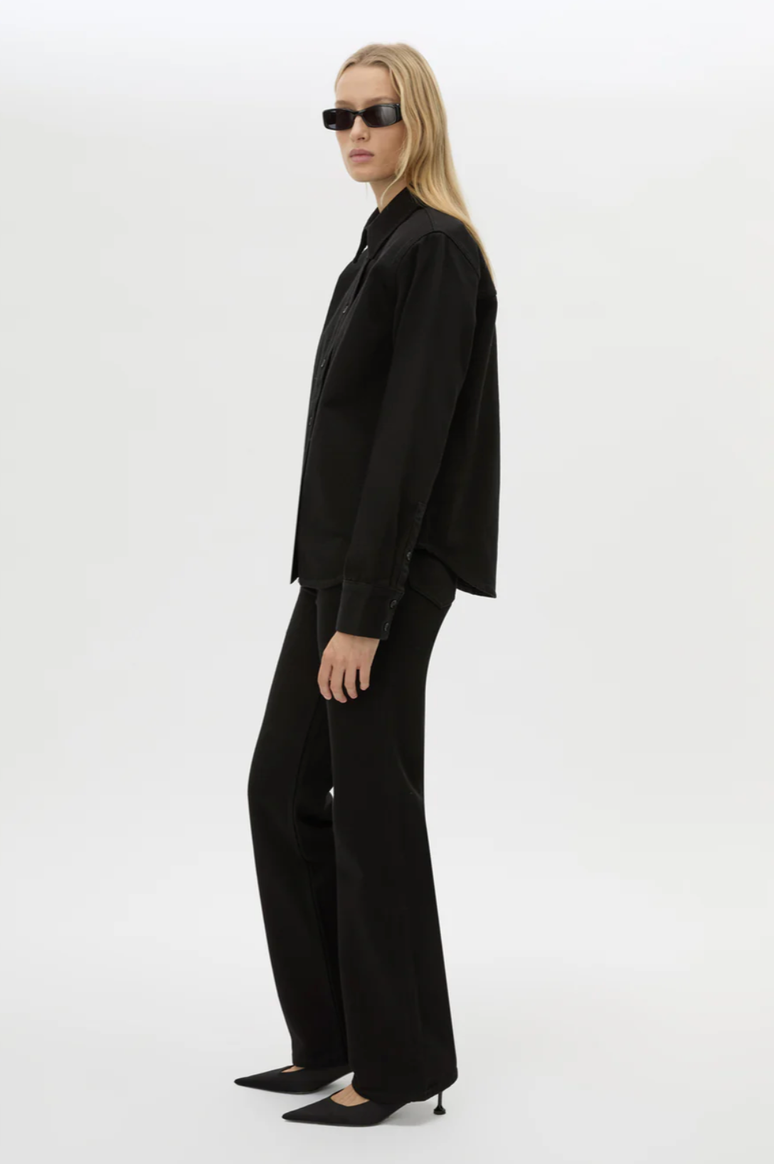 Person wearing a black suit and sunglasses on a white background