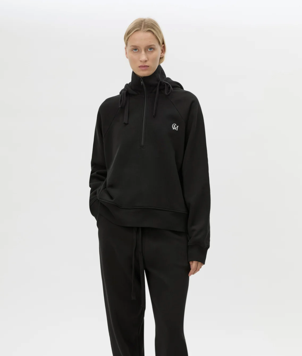 Person wearing a black hoodie with a logo on a white background