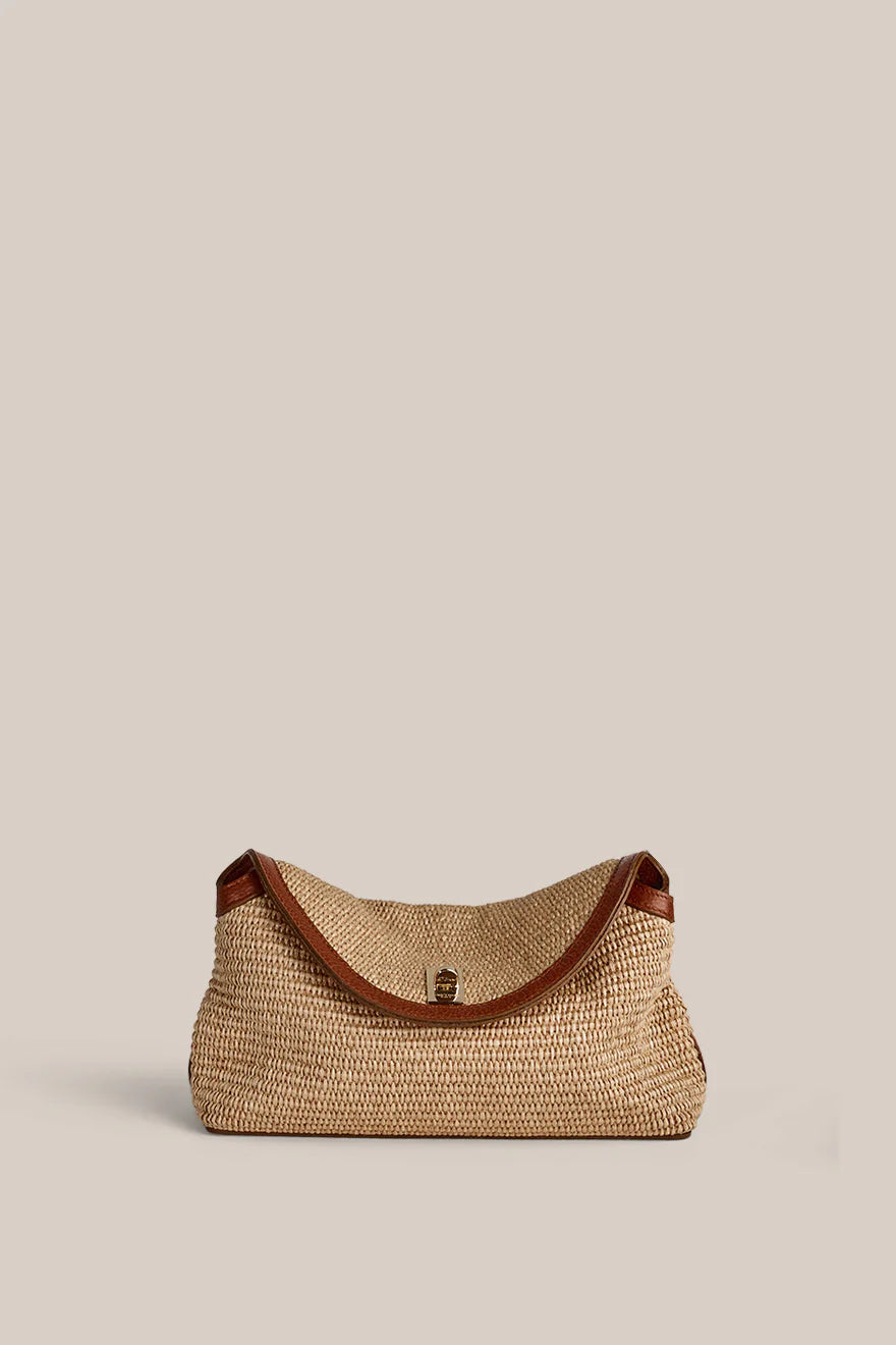 Woven handbag with brown leather trim on a beige background