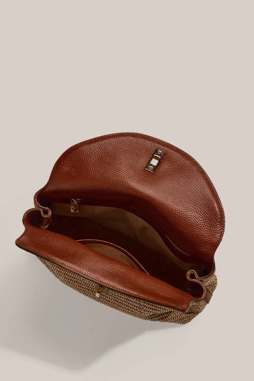 Brown leather handbag with woven base on a beige background