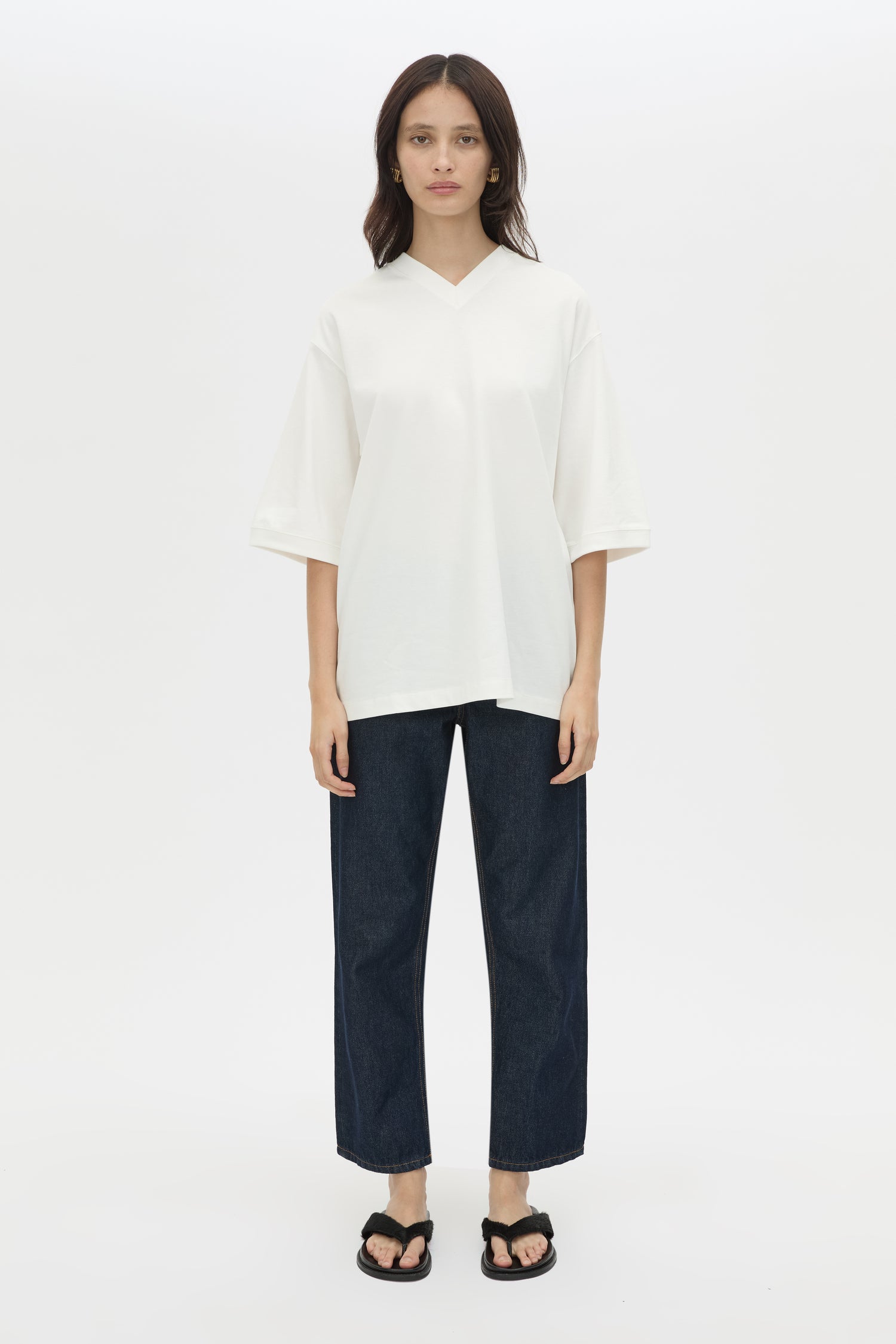 Woman wearing a white top and dark pants on a white background