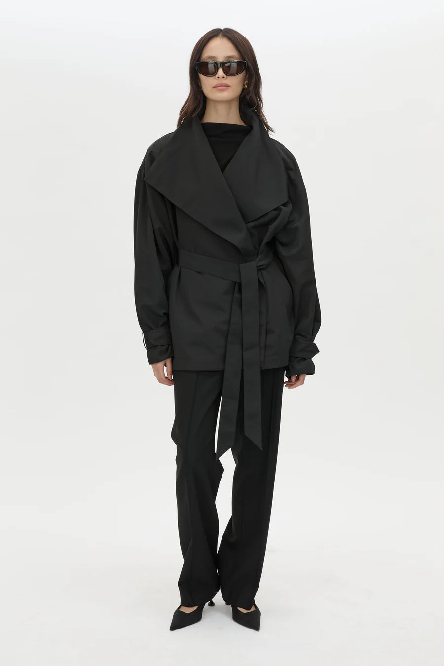 Woman wearing a black outfit with a belt on a white background