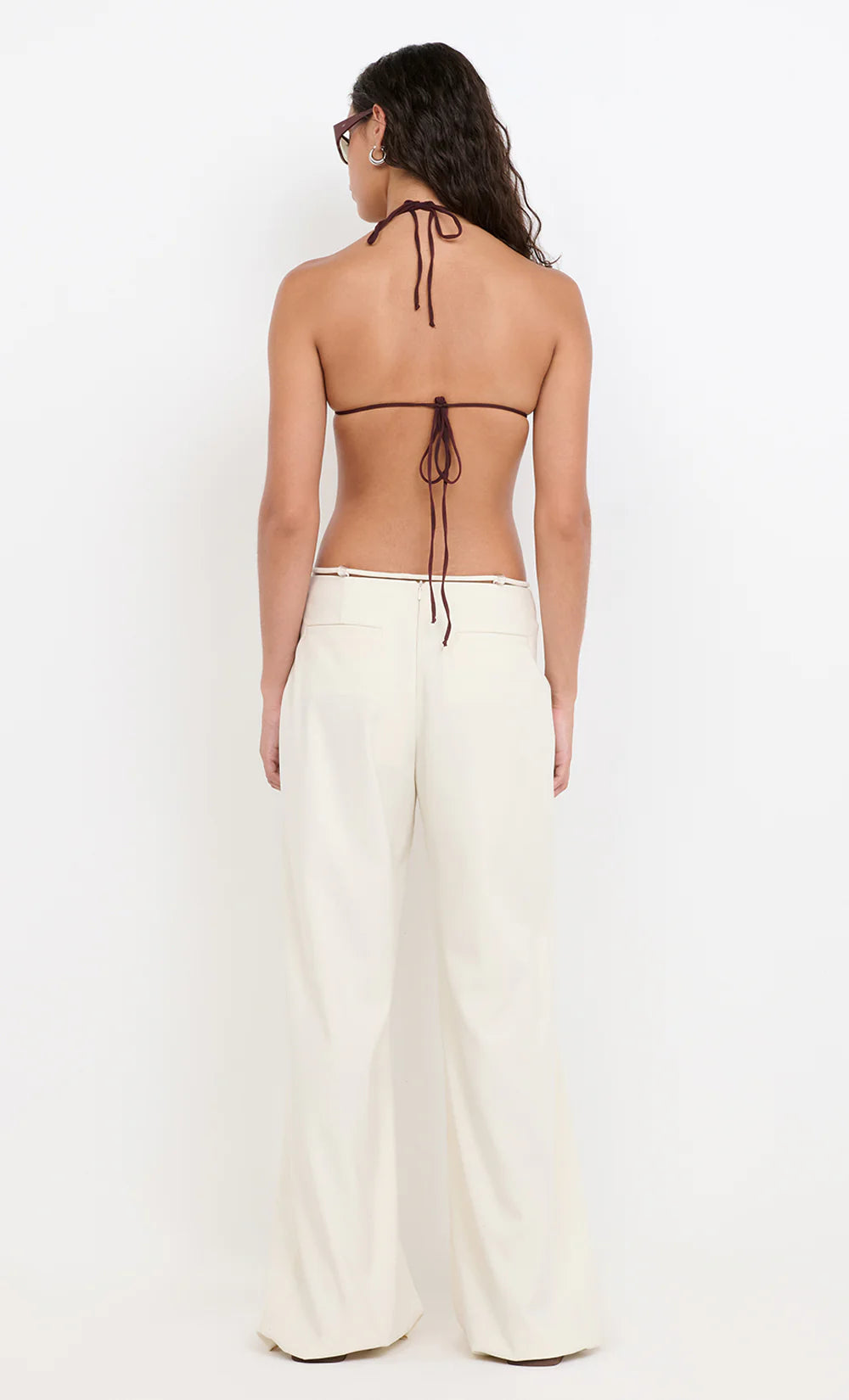 Woman wearing a halter top and white pants on a white background