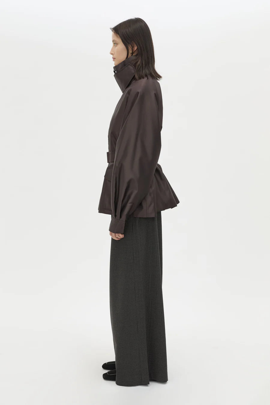 Person wearing a dark brown coat and black pants on a white background