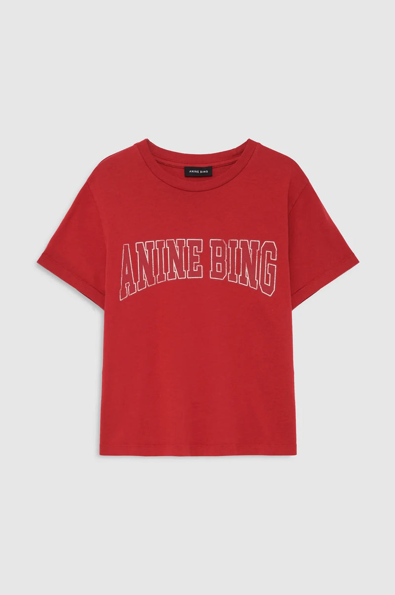 A red short-sleeve t-shirt with 'ANINE BING' printed across the chest in white outlined lettering, shown flat against a light gray background.