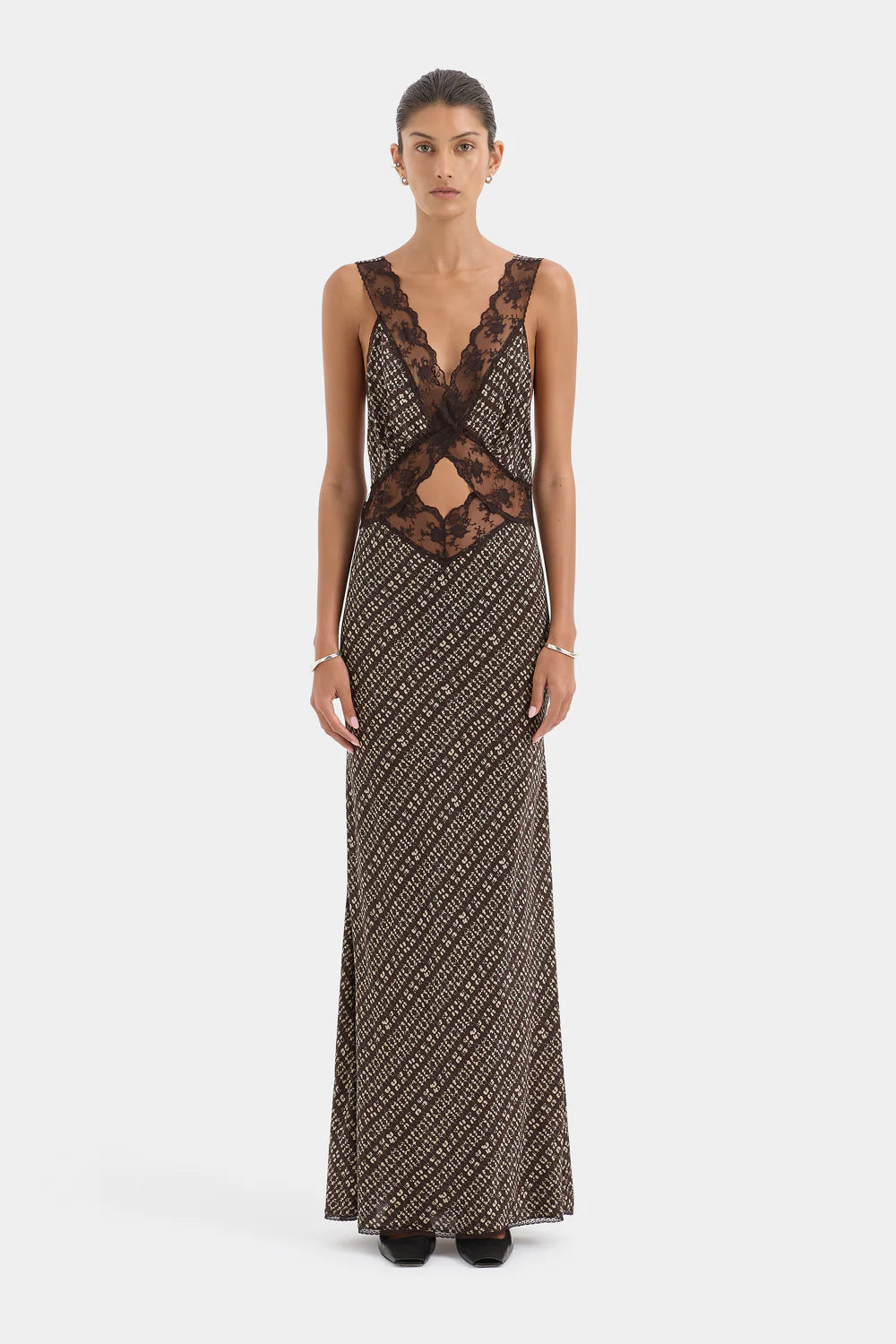 Woman wearing a long, patterned dress with lace detailing on a white background