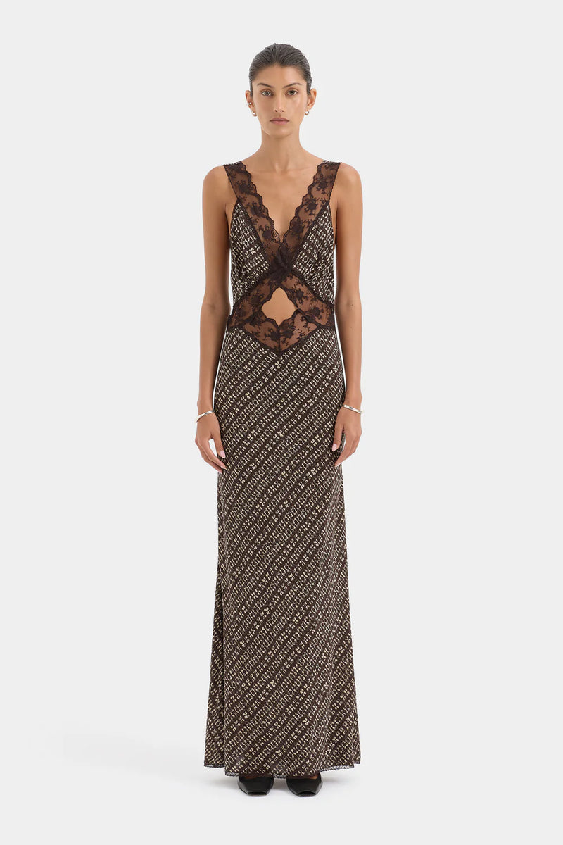 Woman wearing a long, patterned dress with lace detailing on a white background
