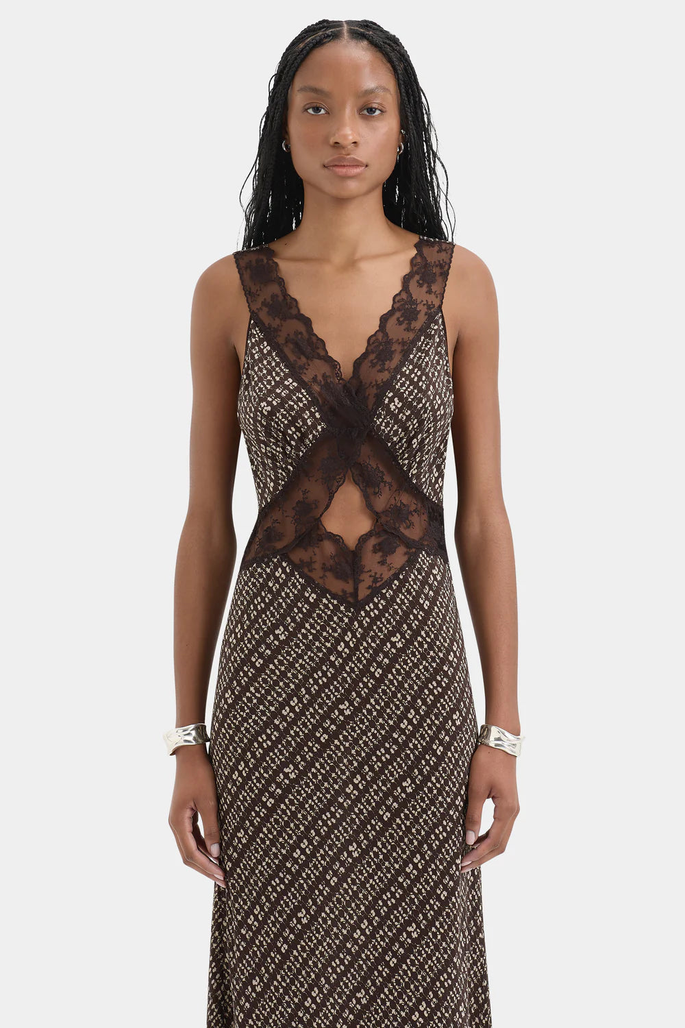 Woman wearing a patterned dress with lace detailing on a white background