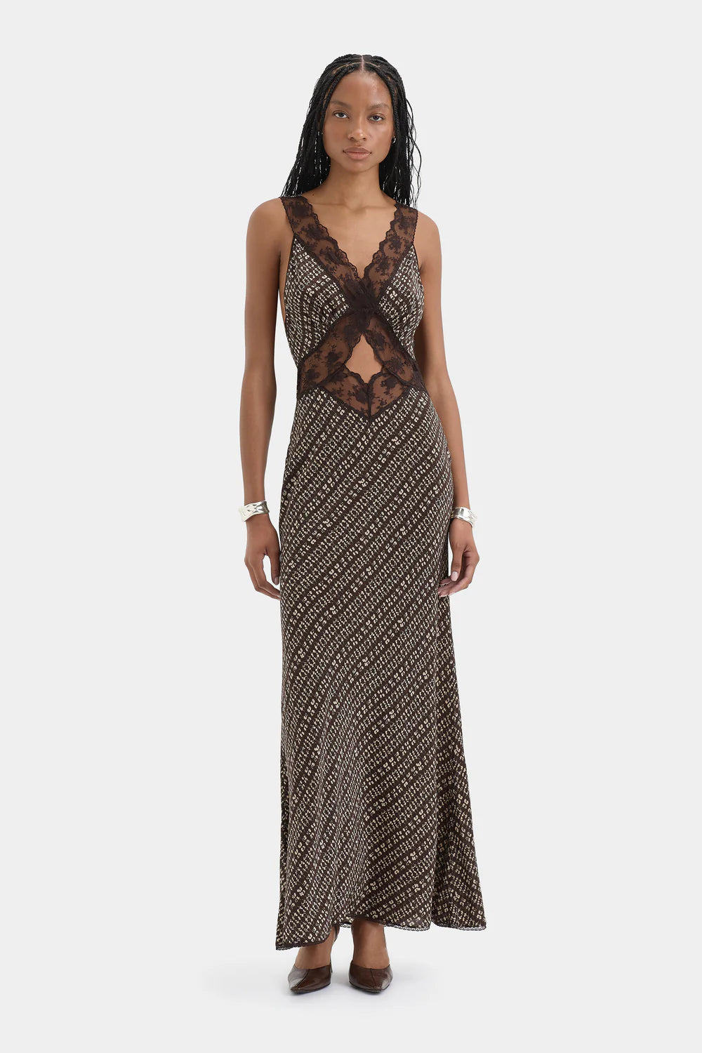 Woman wearing a patterned dress with lace detailing on a white background