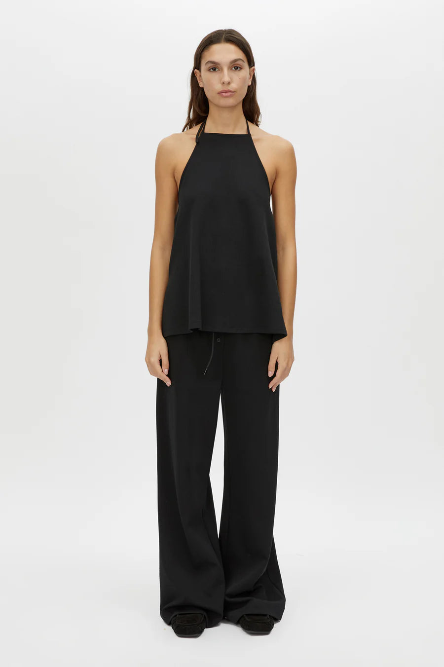 Woman wearing a black halter top and wide-leg pants on a white background