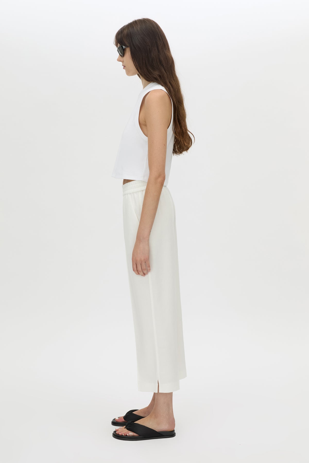 Woman wearing a white sleeveless top and pants on a white background