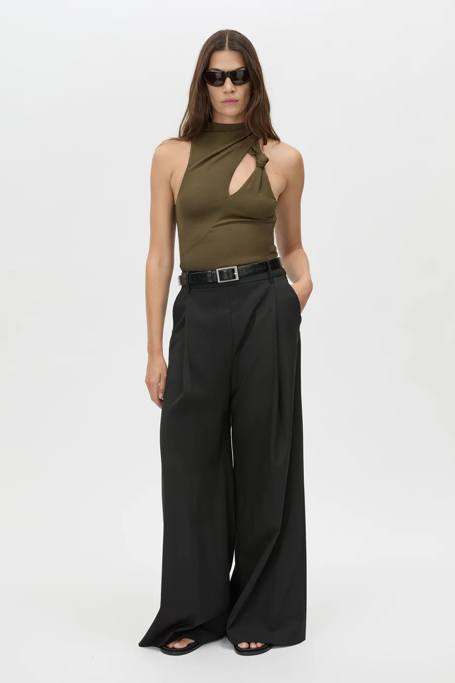 Woman wearing a green halter top and black wide-leg pants on a white background