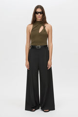 Woman wearing a green halter top and black wide-leg pants on a white background