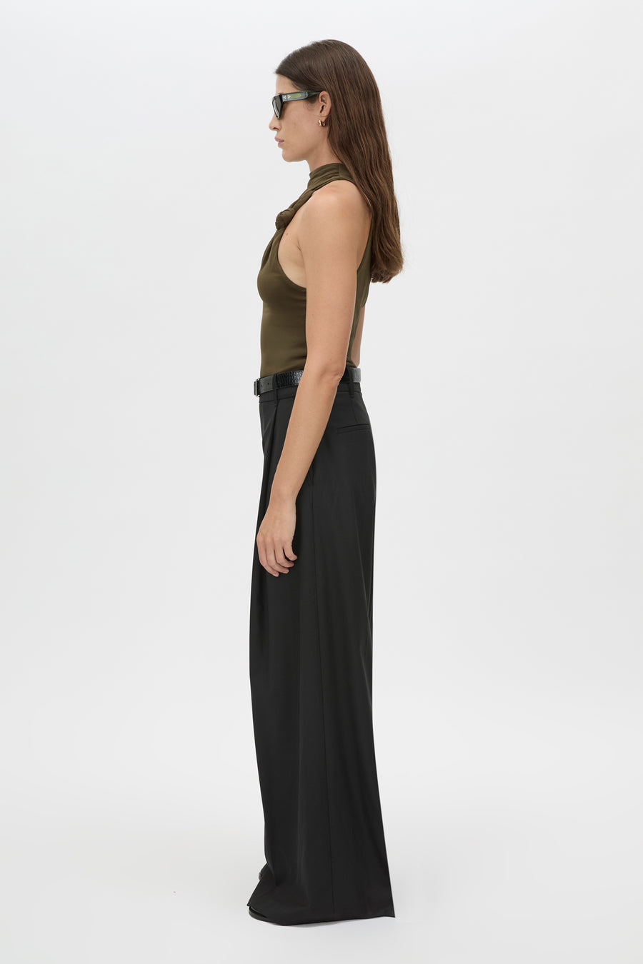 Woman wearing a green top and black pants on a white background