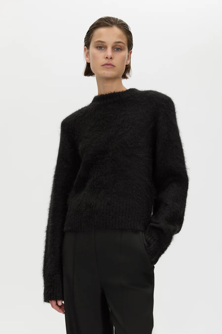 Person wearing a black sweater and pants on a white background