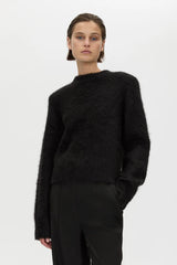 Person wearing a black sweater and pants on a white background