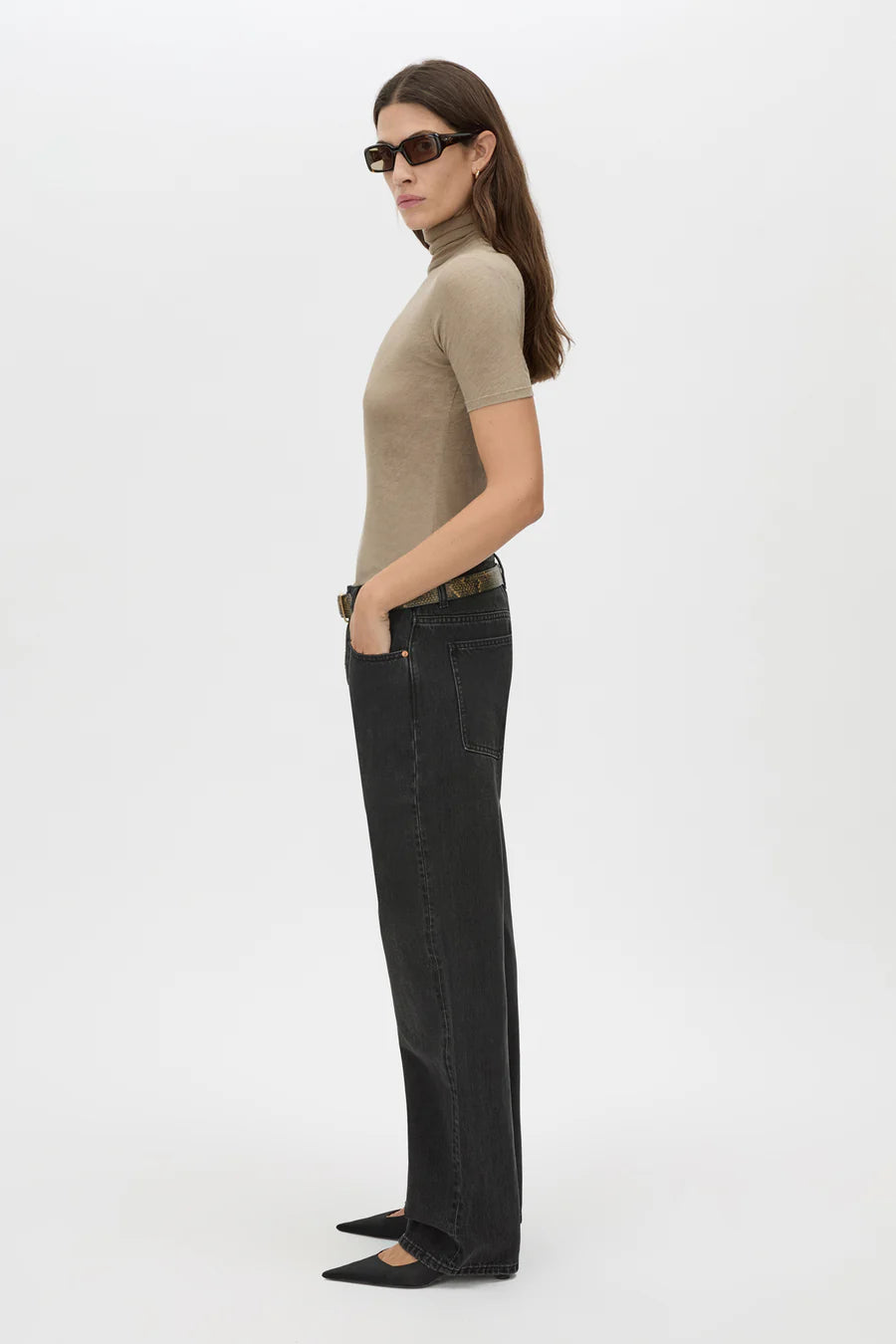 Woman wearing a beige turtleneck and black jeans on a white background