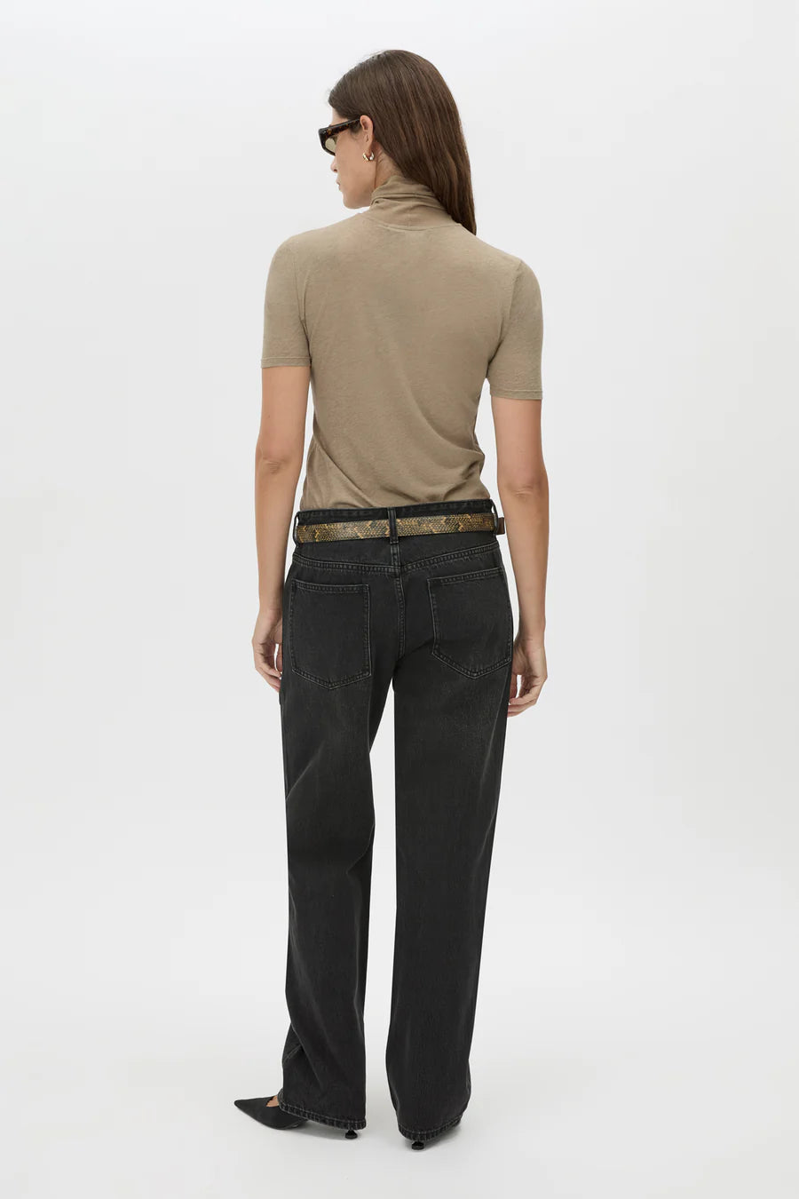 Woman wearing a beige top and black pants on a white background