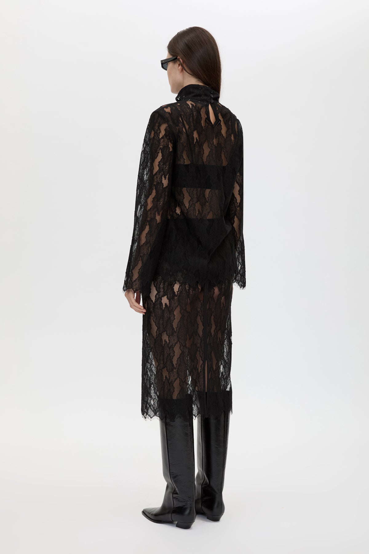 Person wearing a black lace dress on a white background
