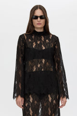 Woman wearing a black lace dress with sheer sleeves on a white background