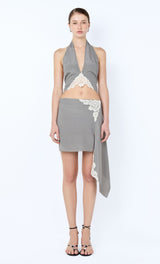 Woman wearing a gray halter top with lace details and a matching skirt on a white background