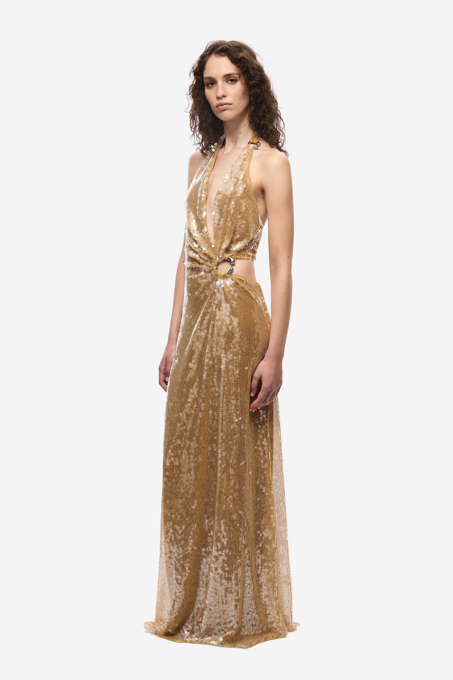 Woman wearing a gold sequin dress on a white background