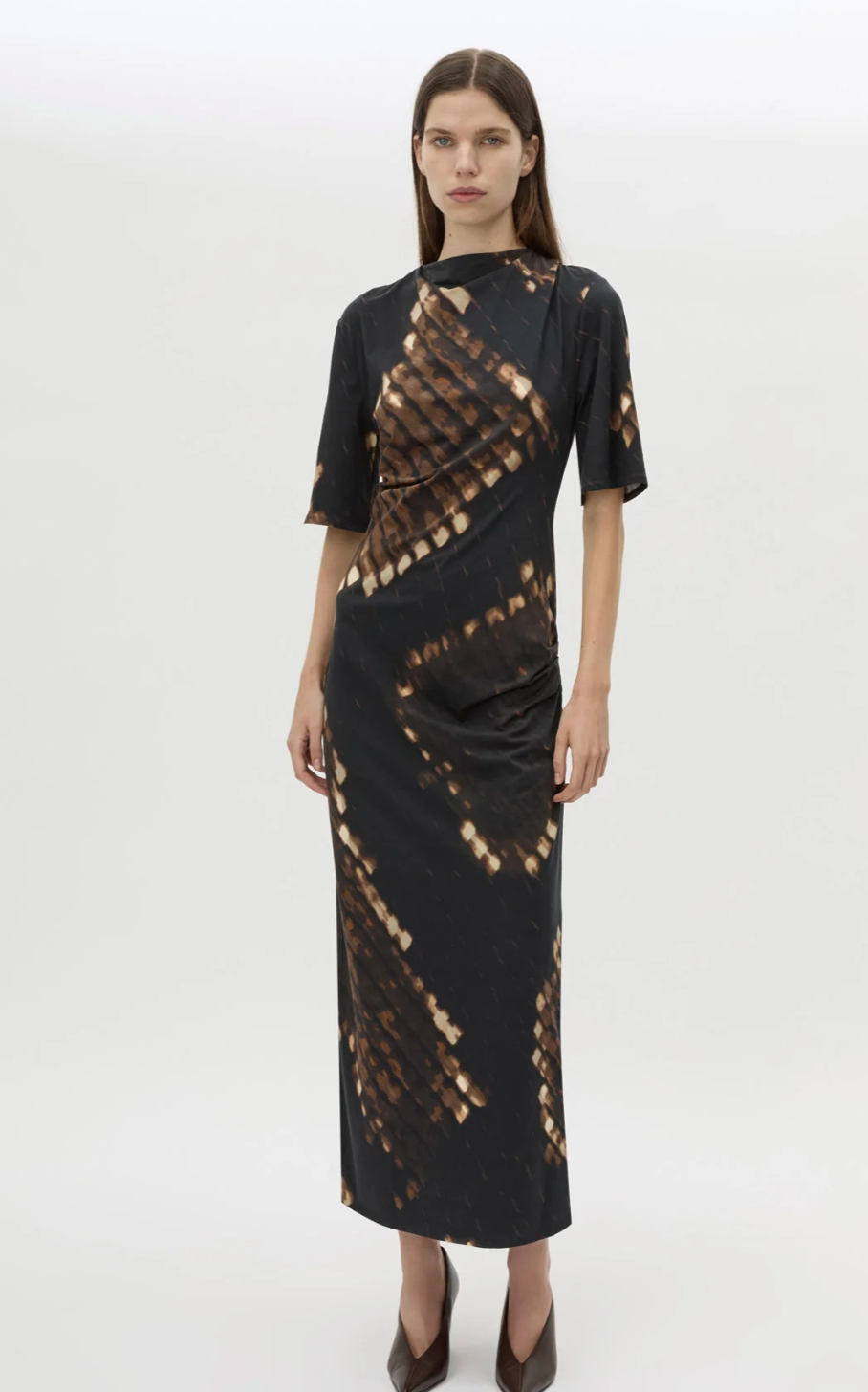 Model wearing a black dress with a pattern on a white background