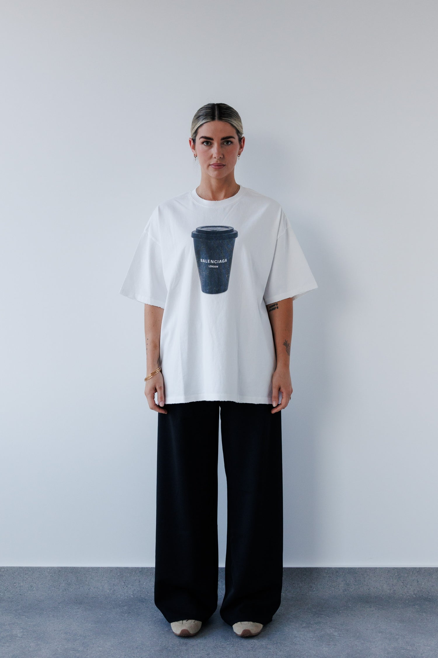 Person wearing a white t-shirt with a graphic design against a plain background