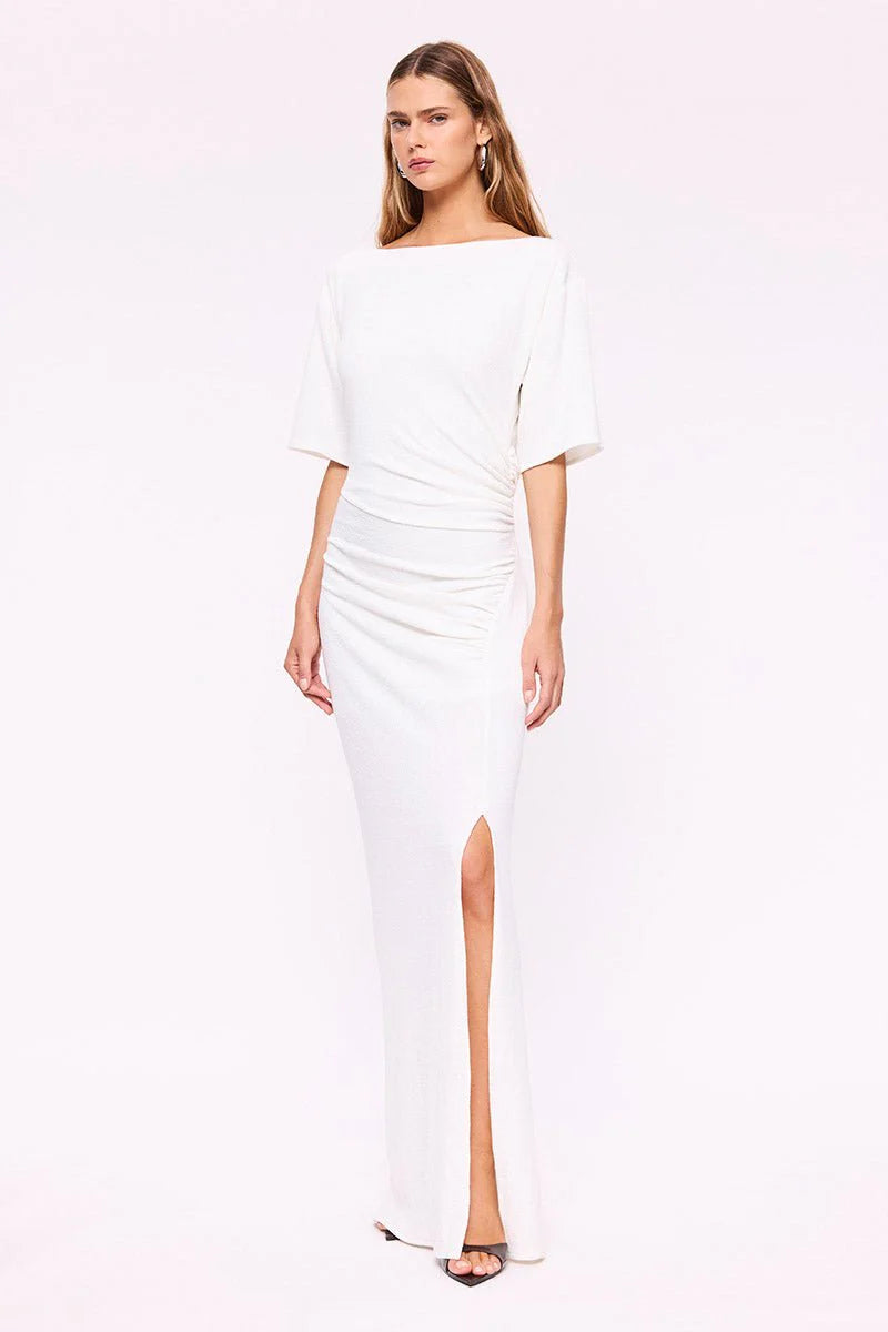 Woman wearing a white dress with a slit on a white background