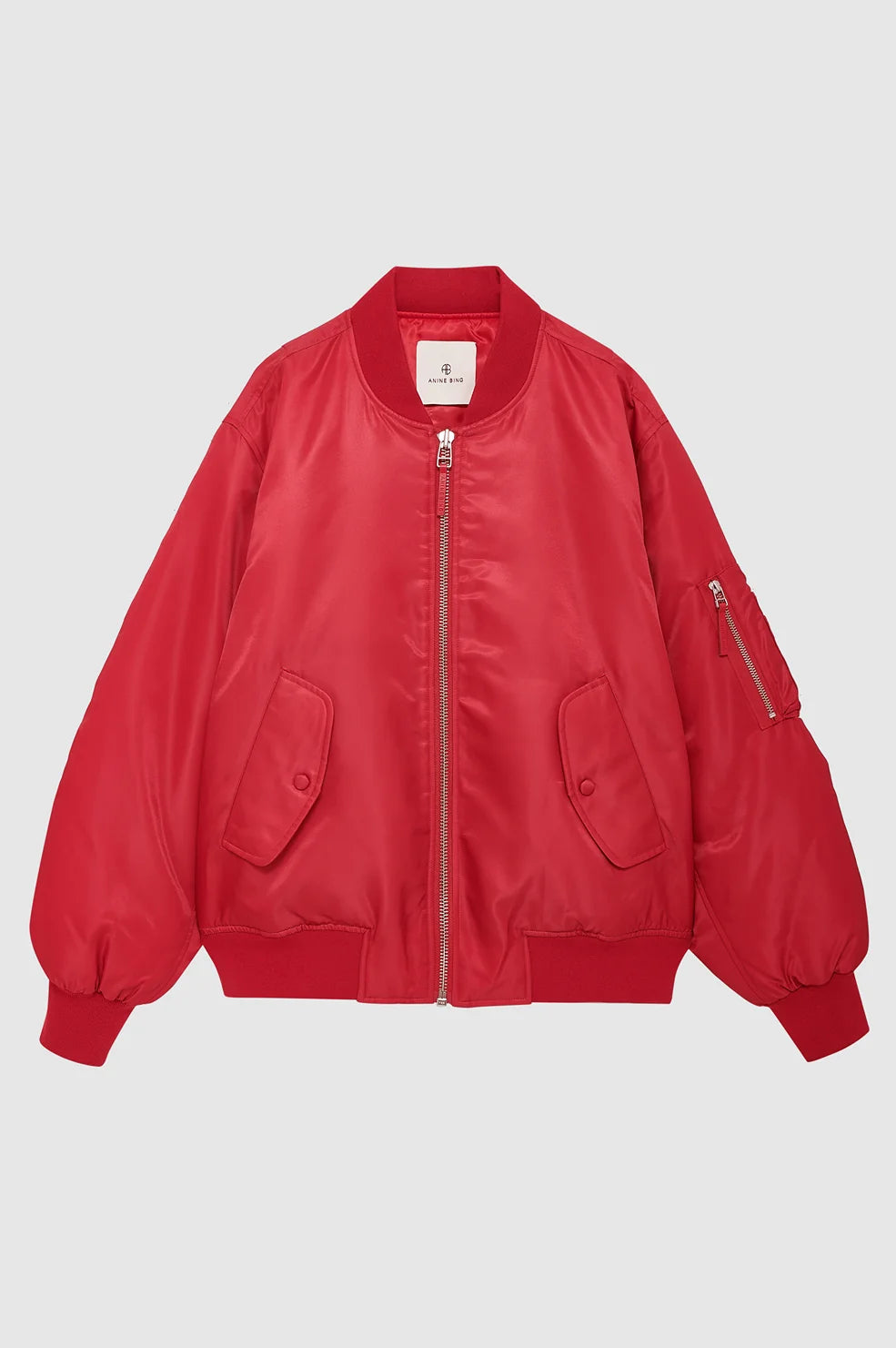 A red bomber jacket with a full front zipper, ribbed collar, cuffs, and hem, featuring two large front flap pockets and a zippered sleeve pocket, shown against a light gray background.
