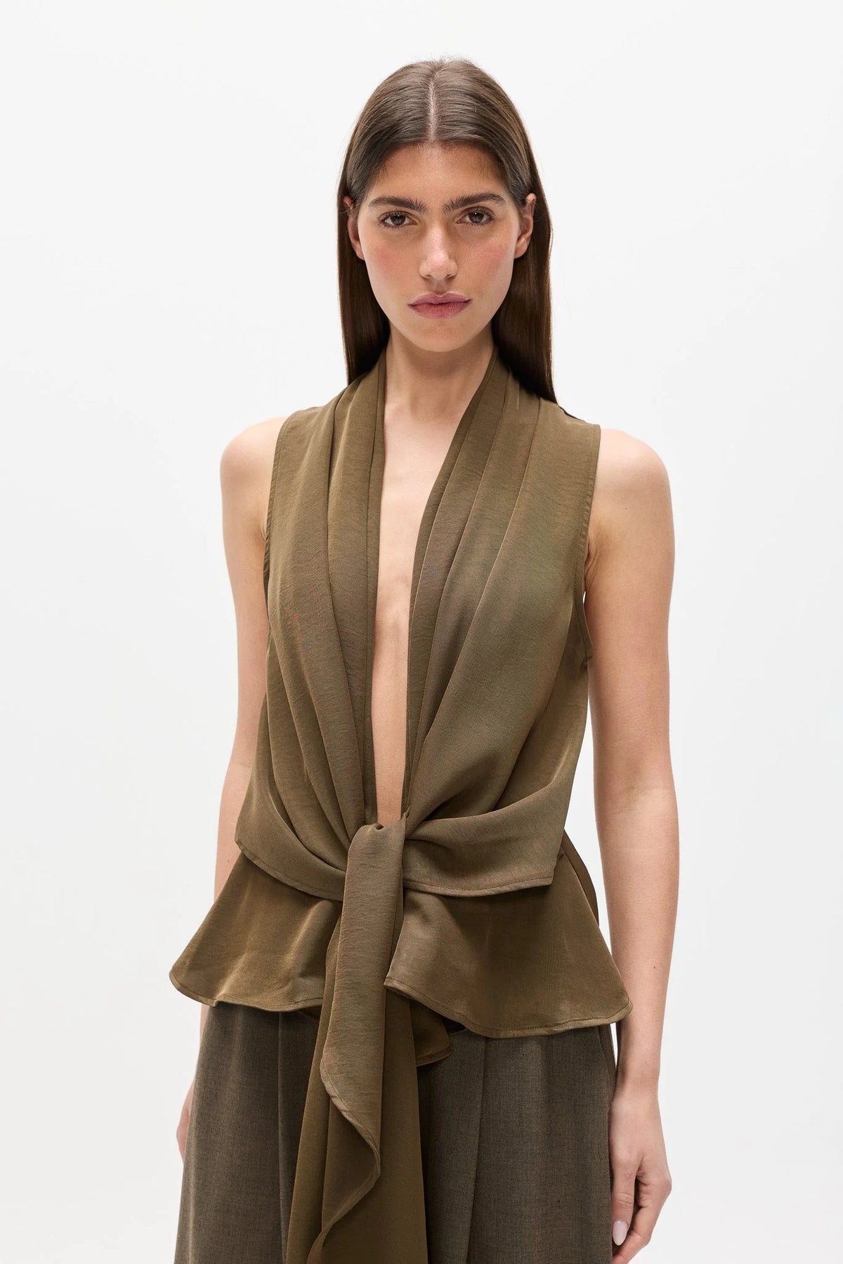 A model wearing a sleeveless olive green wrap top with a deep V-neck and tied waist, paired with matching olive green pants, against a plain light gray background.