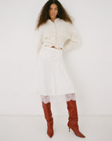 Woman wearing a white outfit with red boots on a white background