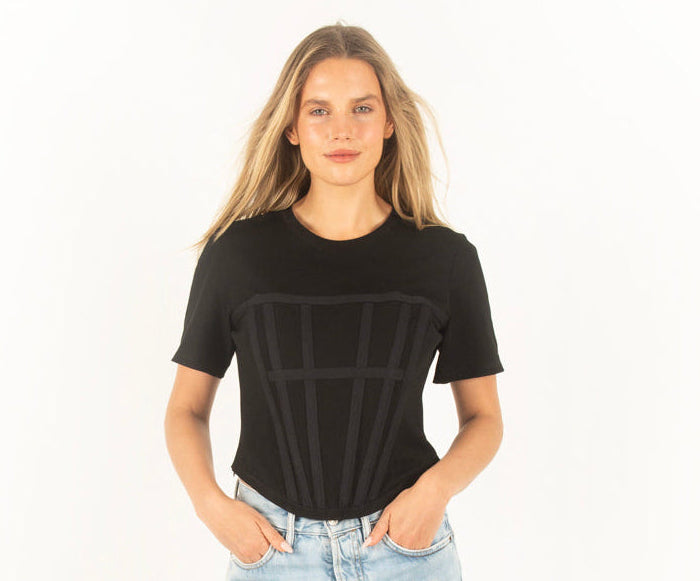 Person wearing a black corset t-shirt and light blue jeans on a white background