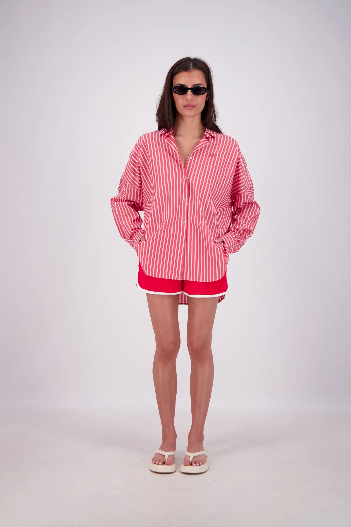 Woman wearing a red and white striped shirt and shorts on a white background
