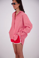 Woman wearing a red and white striped shirt and shorts on a plain background