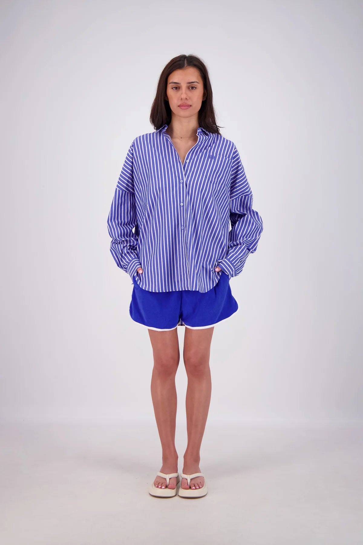 Woman wearing a blue and white striped shirt and shorts on a white background