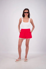 Woman wearing a white tank top and red shorts on a white background