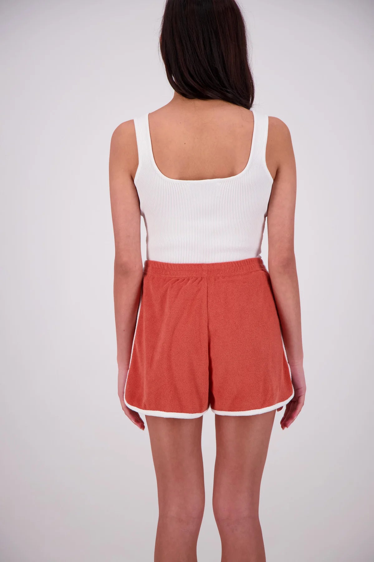 Person wearing a white tank top and red shorts on a plain background