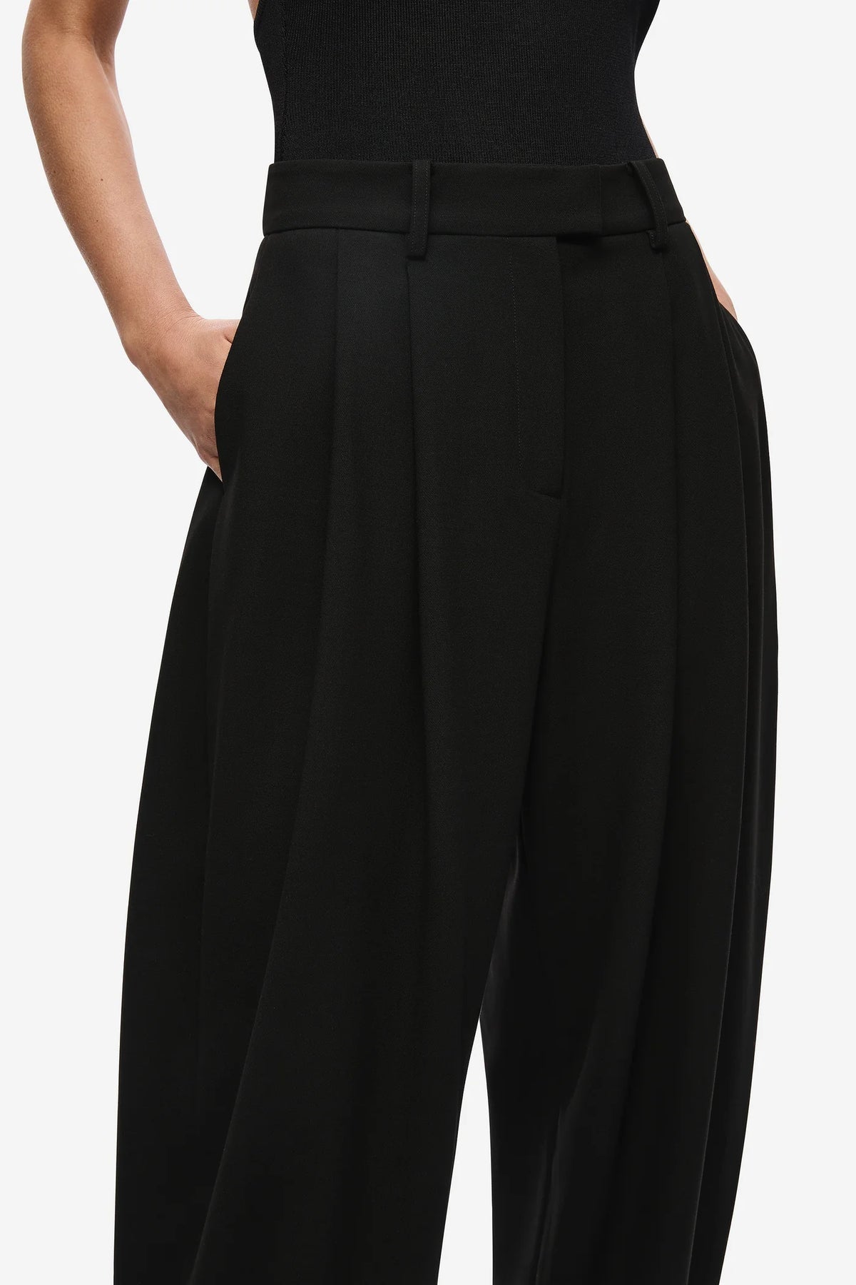 Black high-waisted pants worn by a person on a white background