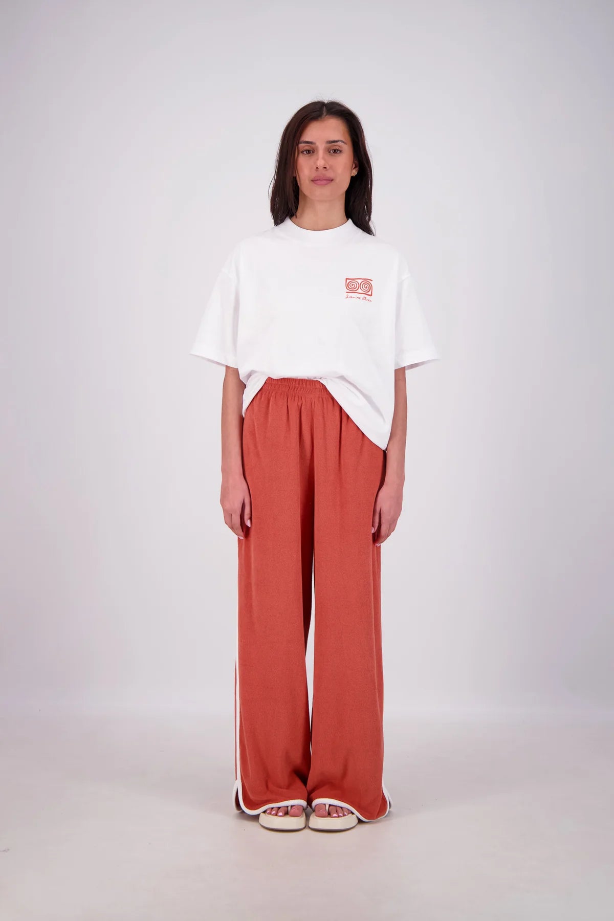 Person wearing a white oversized t-shirt and red pants on a white background