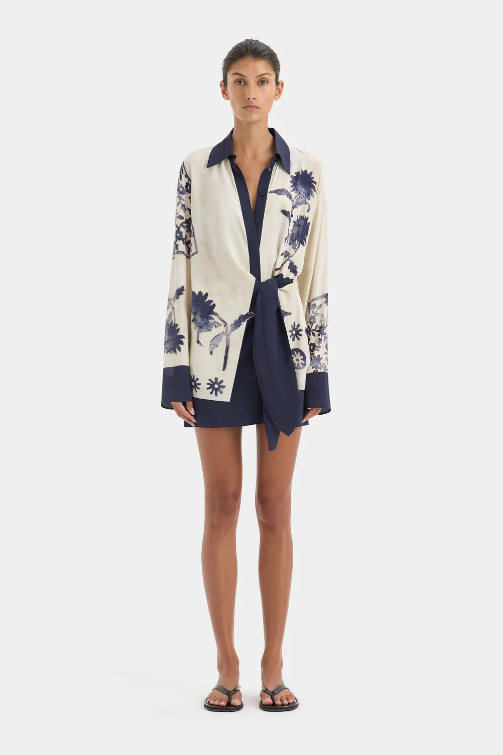 Woman wearing a floral patterned cardigan over a dress on a white background