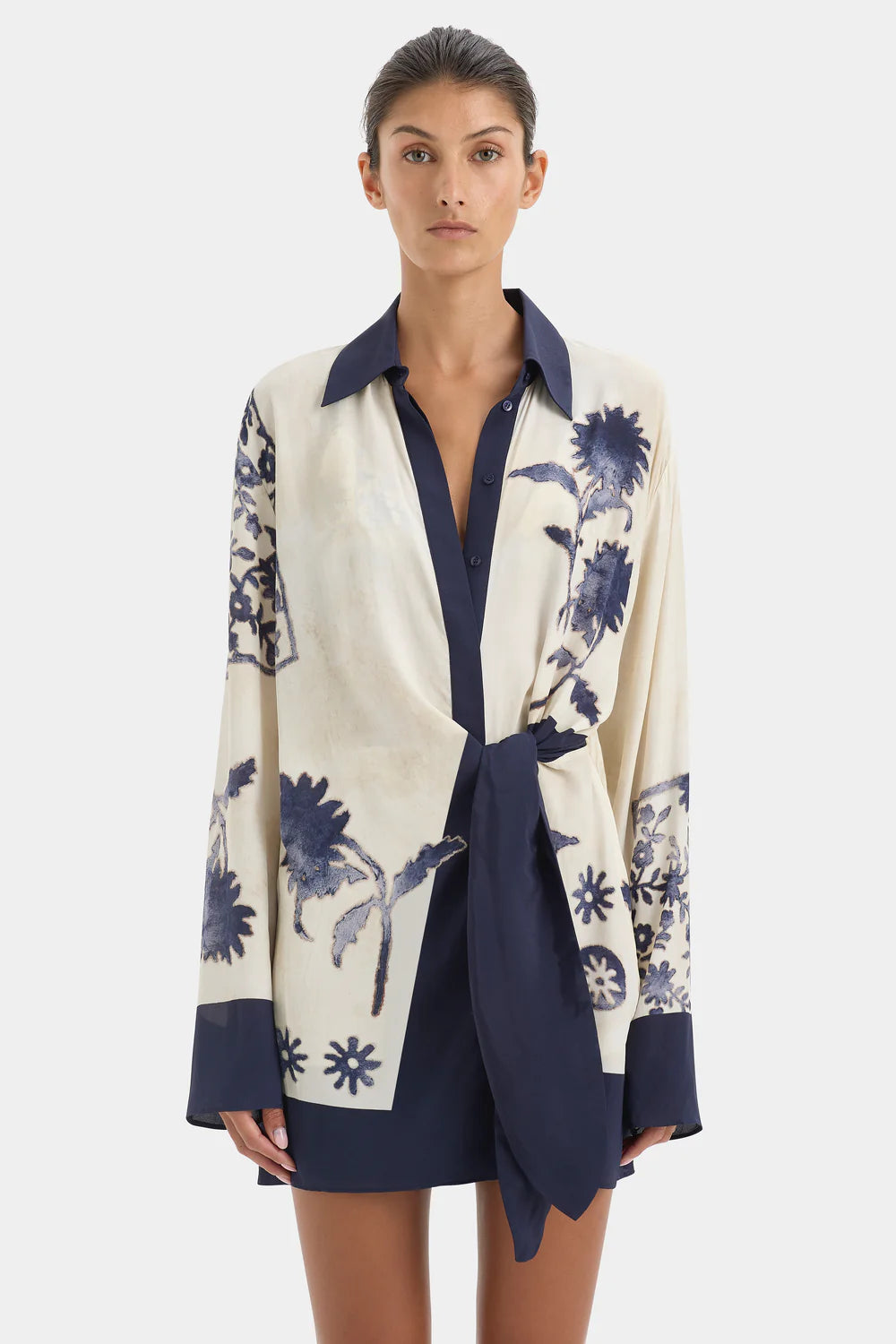 Woman wearing a white and navy floral dress with a white background