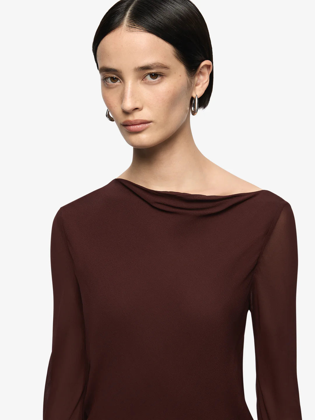 Woman wearing a brown long-sleeve top against a light gray background