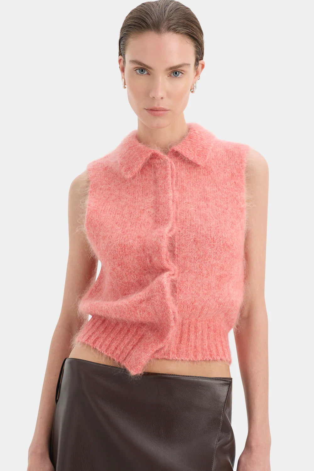Woman wearing a pink knitted vest against a white background