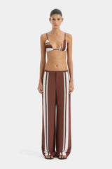 Woman wearing a brown and white striped bikini with matching pants on a white background