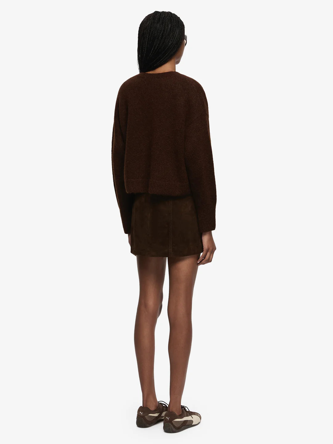 Person wearing a brown sweater and skirt set on a white background
