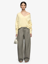 Woman wearing a yellow sweater and gray pants on a white background