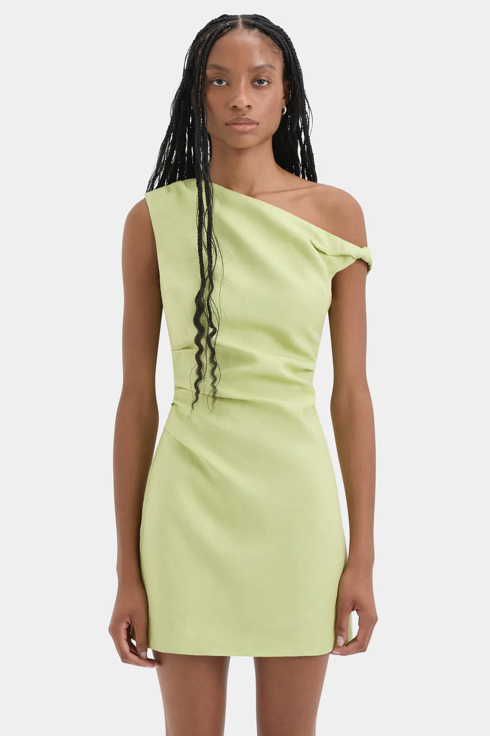 A model wearing a light lime green one-shoulder bodycon mini dress against a plain light gray background.