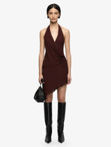 Woman wearing a brown halter dress and black knee-high boots on a white background