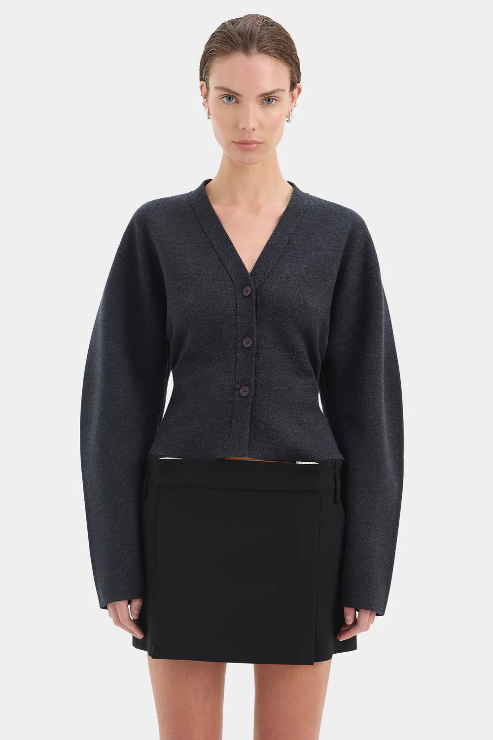 Woman wearing a dark gray cardigan and black skirt on a white background